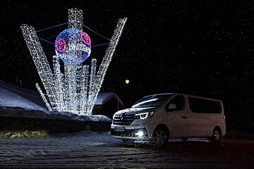 A white van is parked in front of a christmas decoration