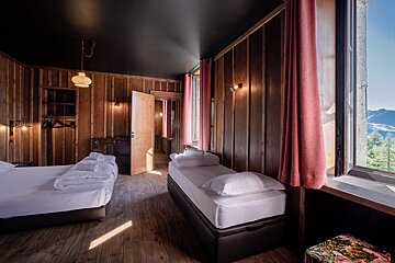 A bedroom with two beds and a window with a view of the mountains