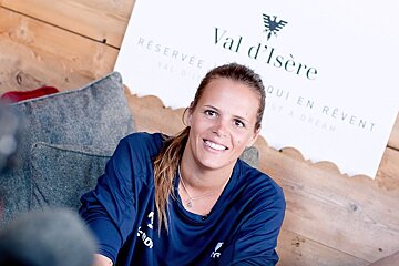 A woman sitting in front of a sign that says val d' isere