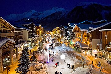A snowy town at night with mountains in the background