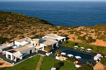 A large house sits on a hill overlooking the ocean