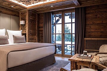 A bedroom with a bed a chair and a table