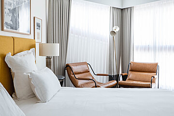 A hotel room with two chairs and a lamp