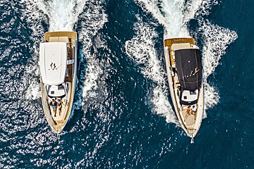 Two boats are floating in the ocean one of which has the word yacht on the side
