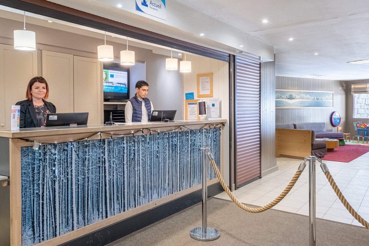 A man and a woman are at a hotel reception desk