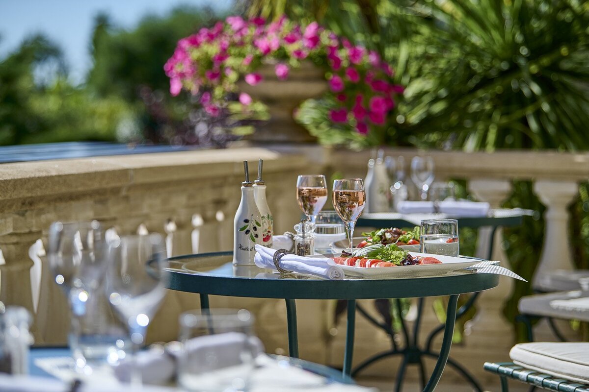 A bottle of olive oil sits on a table next to a plate of food