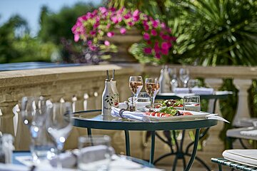 A bottle of olive oil sits on a table next to a plate of food