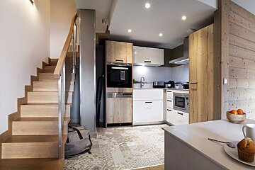 A kitchen with a staircase leading up to the second floor