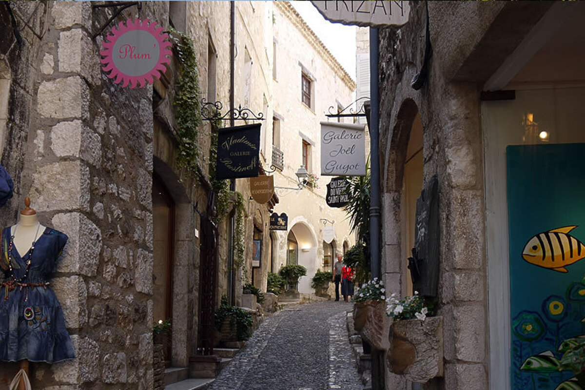 A narrow street with a sign that says galerie art giuge