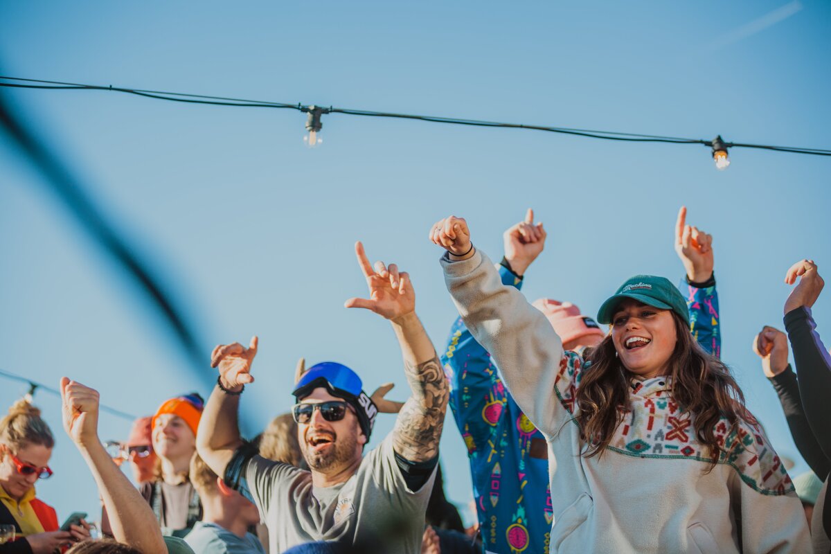 A woman wearing a patagonia hat is cheering with her hands in the air