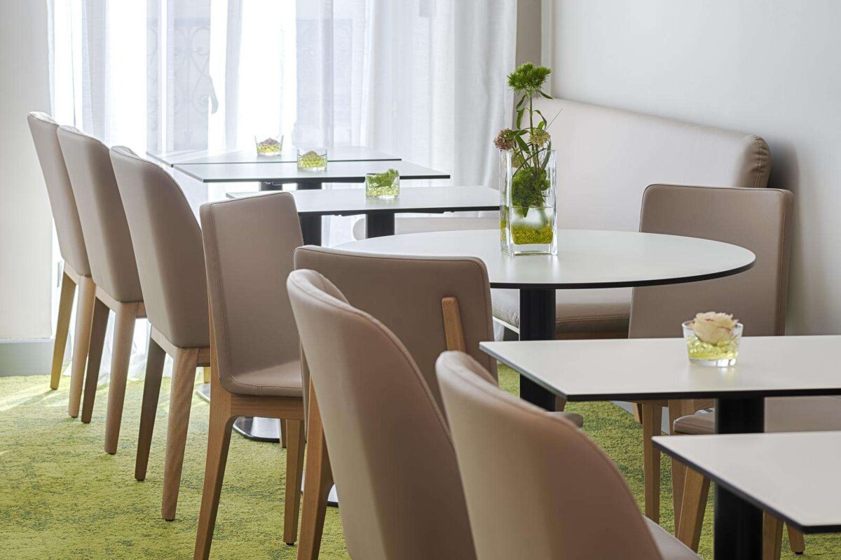 A row of tables and chairs with vases of flowers on them