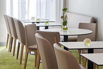 A row of tables and chairs with vases of flowers on them