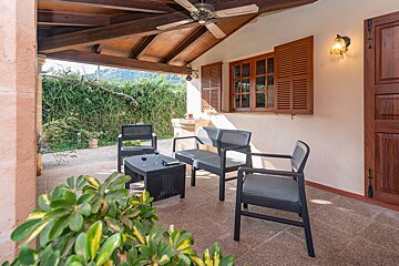 A patio with a table and chairs under a ceiling fan