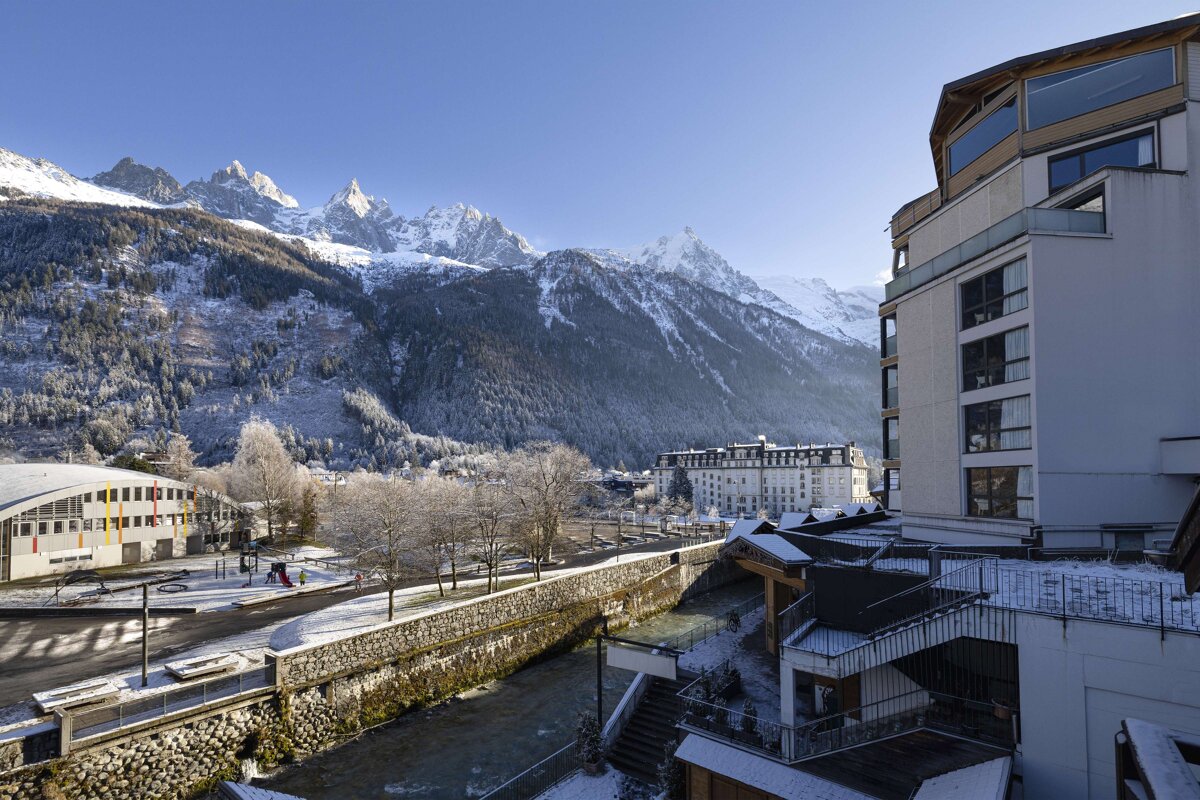 A large white building with a river and mountains in the background