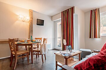 A living room with a table and chairs and a television