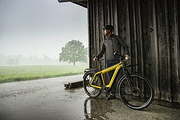 A man leaning against a wooden wall with a yellow bike