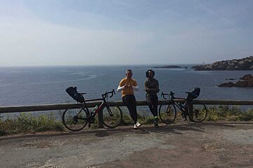 Two people leaning on a railing with their bikes