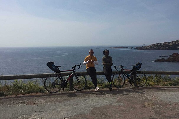 Two people leaning on a railing with their bikes