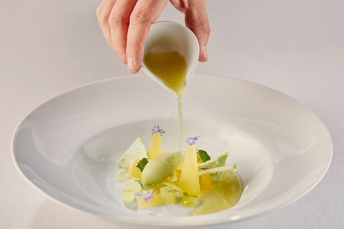 A person pouring liquid into a bowl of food