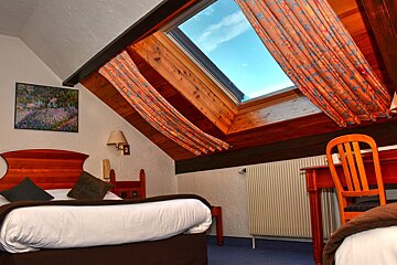 A bedroom with a skylight and a painting of flowers on the wall