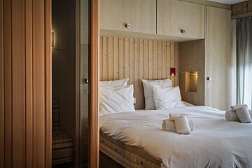 A bed with white sheets and pillows in a room with wood paneling