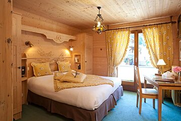 A bedroom with a bed and a desk with the letter r on the headboard
