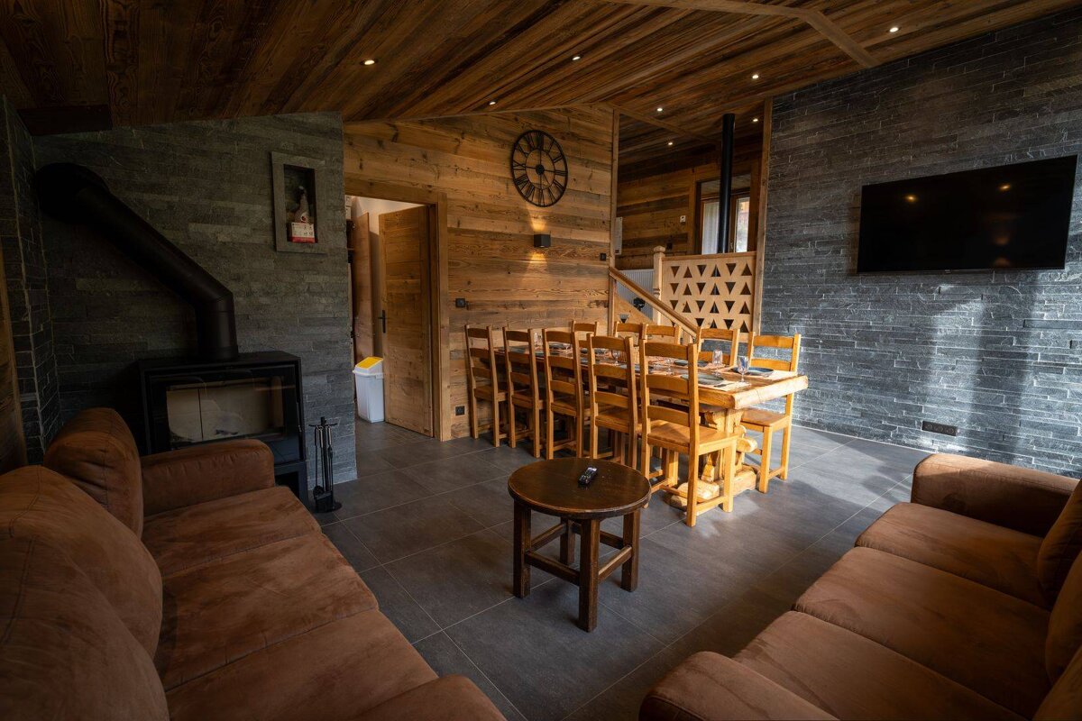 A living room with a table and chairs and a clock on the wall