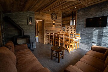 A living room with a table and chairs and a clock on the wall