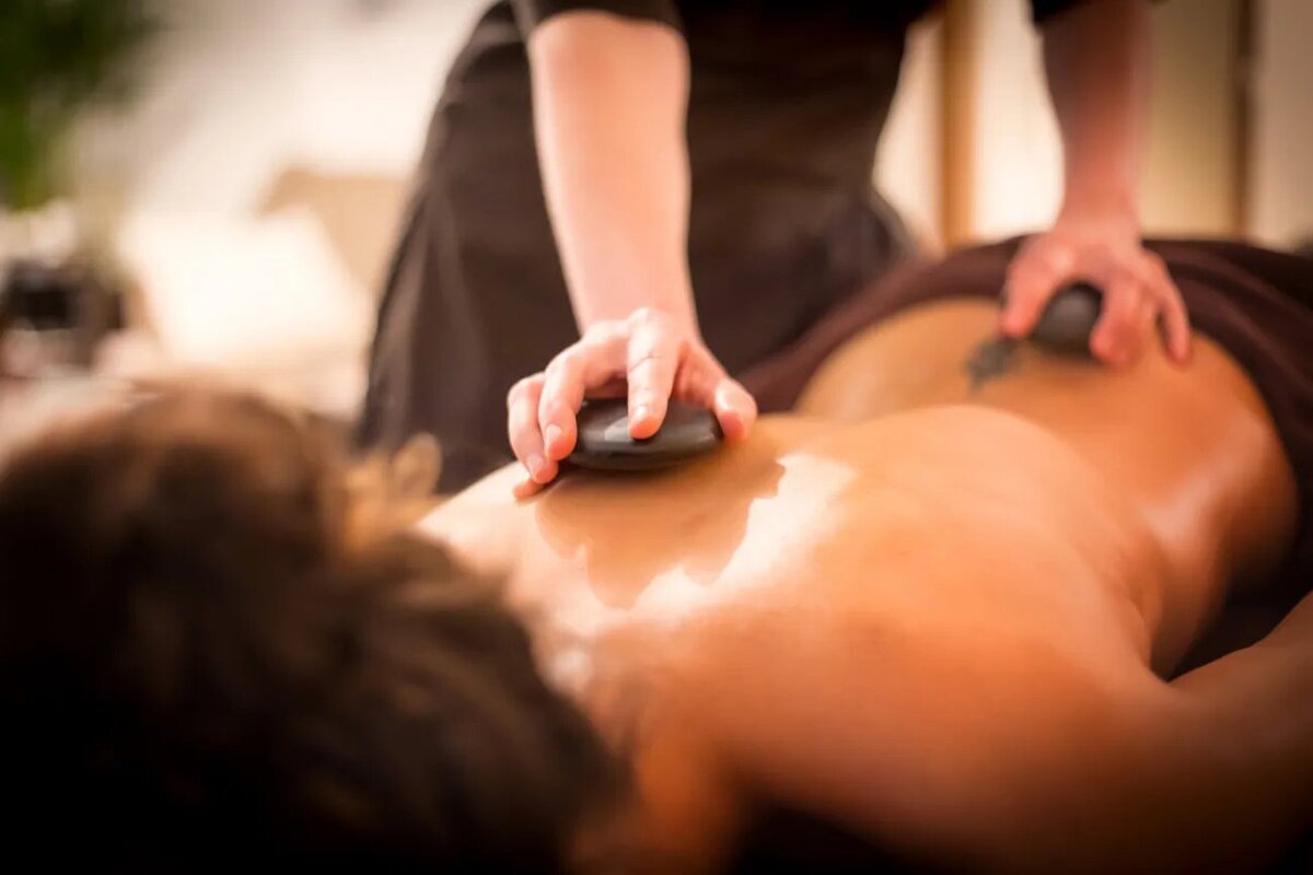 A person is getting a massage with a rock on their back
