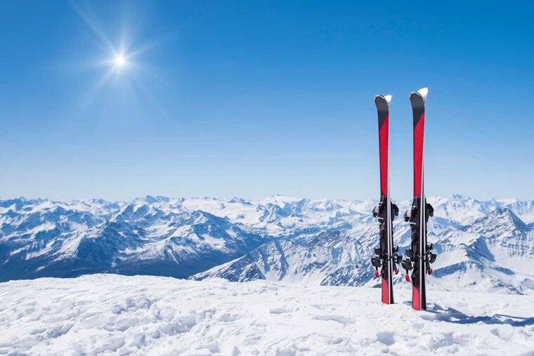 Two skis are sitting on top of a snow covered mountain