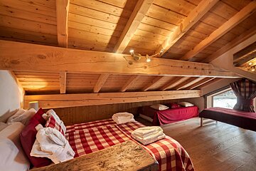 A bedroom with two beds and a wooden ceiling