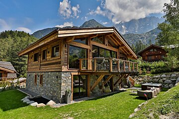 A large wooden house with mountains in the background