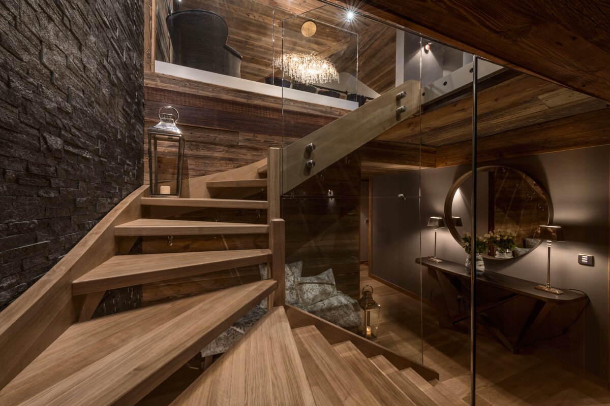 A wooden staircase with a glass railing leading up to the second floor