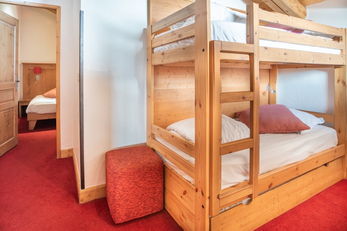 A bunk bed in a room with a red carpet