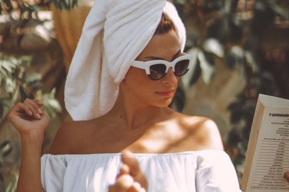 A woman with a towel wrapped around her head is reading a menu