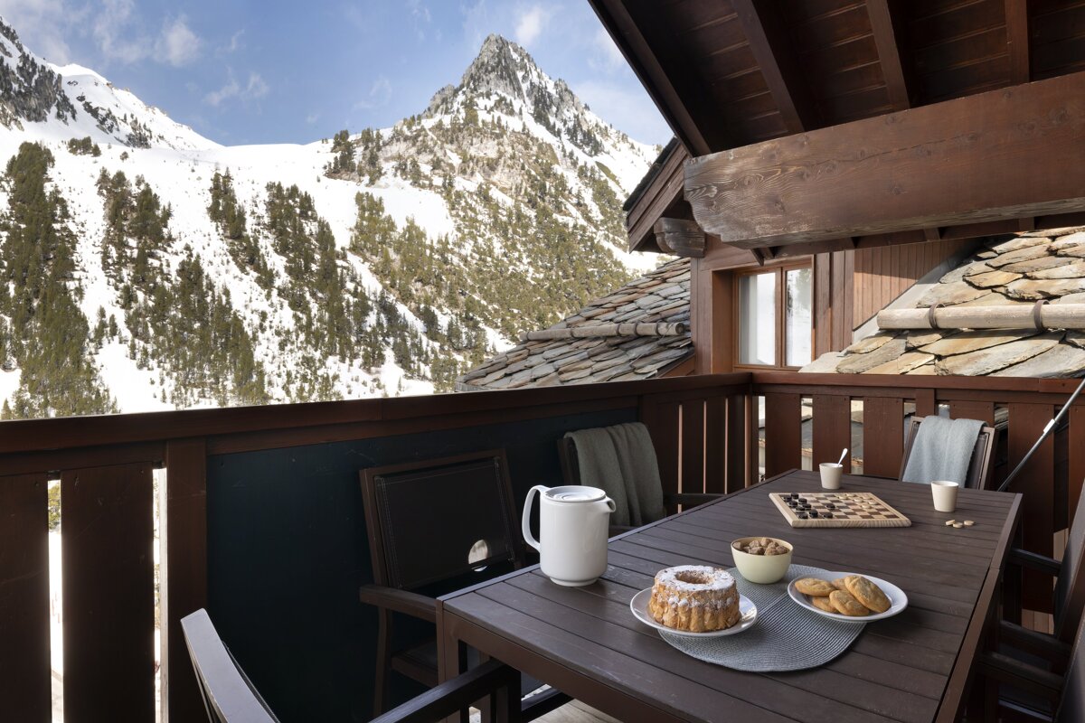 A balcony with a mountain in the background and a table with food on it
