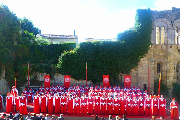 people in red robes in front of castle ruins