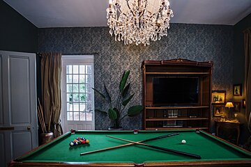 A pool table in a room with a chandelier above it
