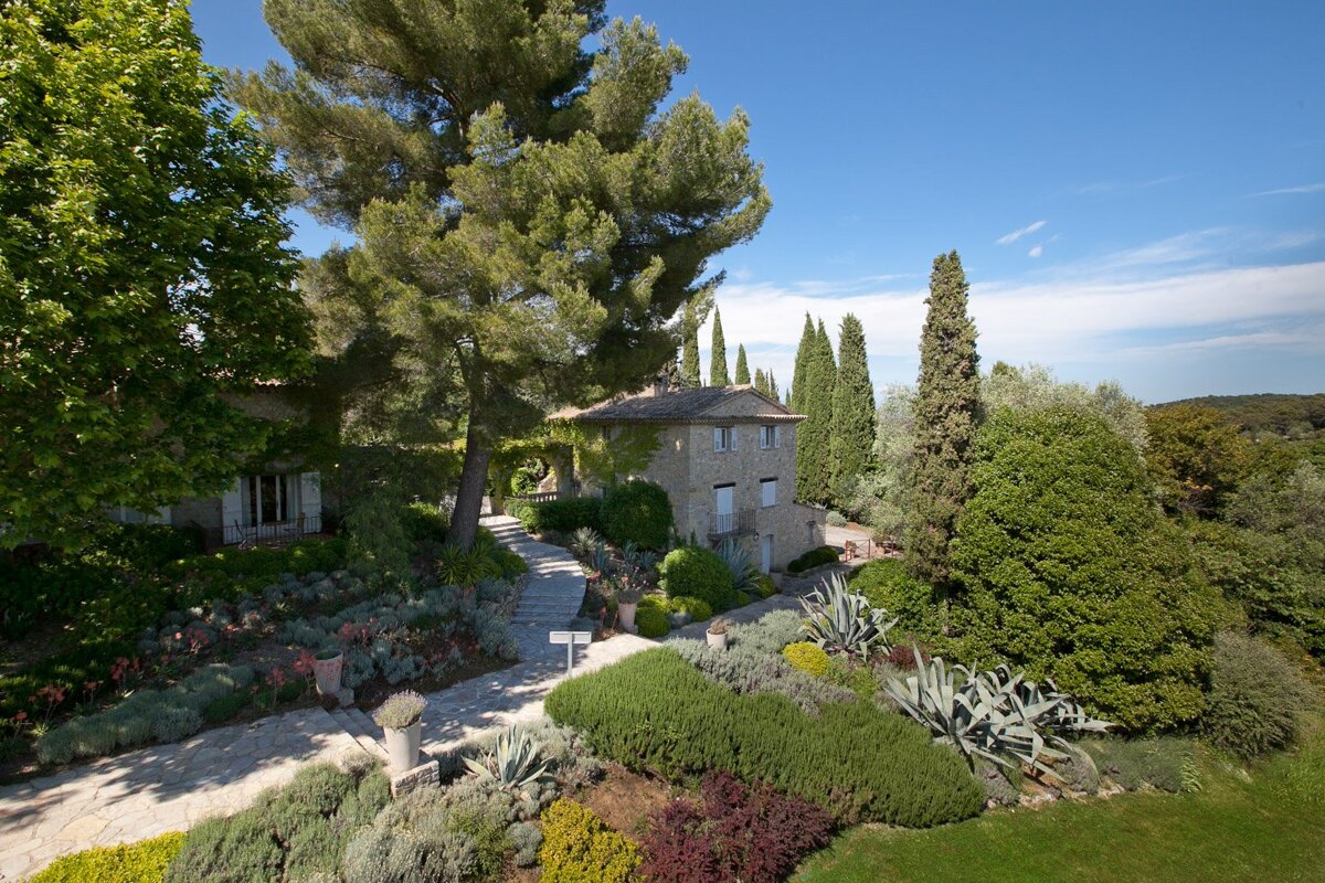 A stone house is surrounded by trees and bushes