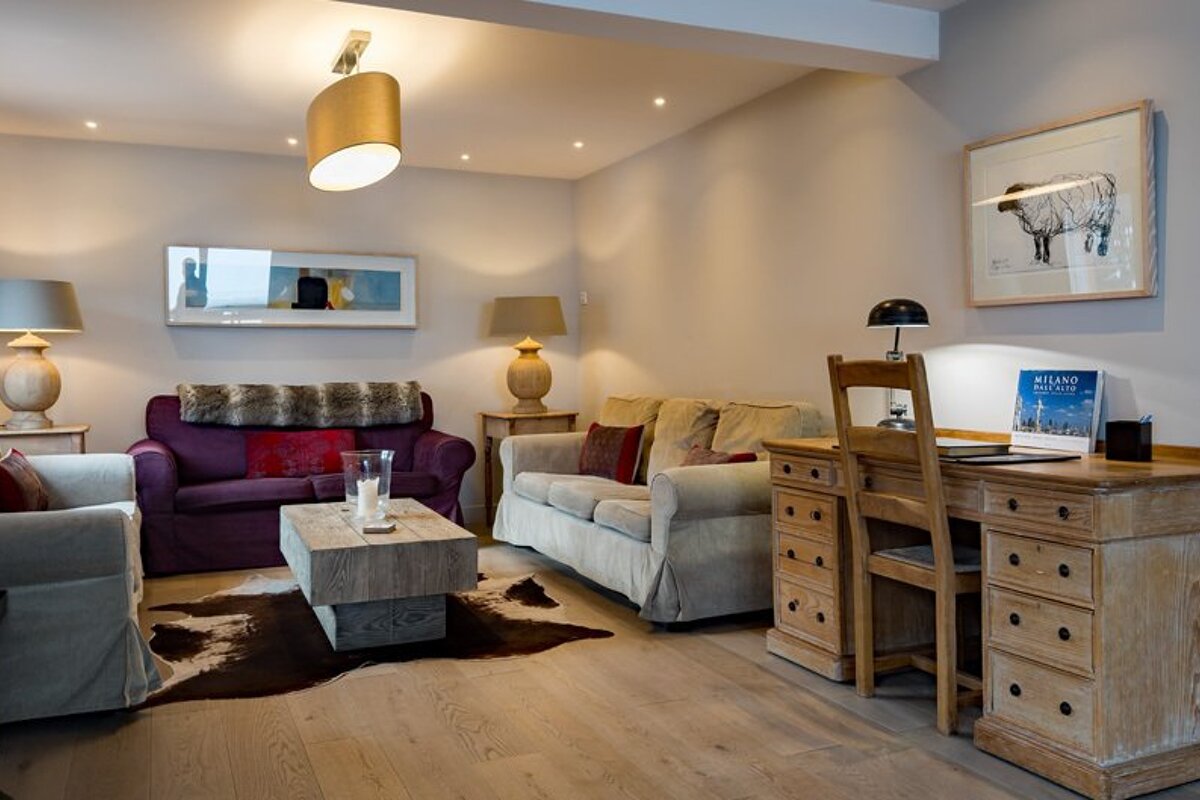 A living room with a purple couch and a desk with a book on it that says 