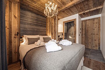 A bedroom with a large bed and a chandelier