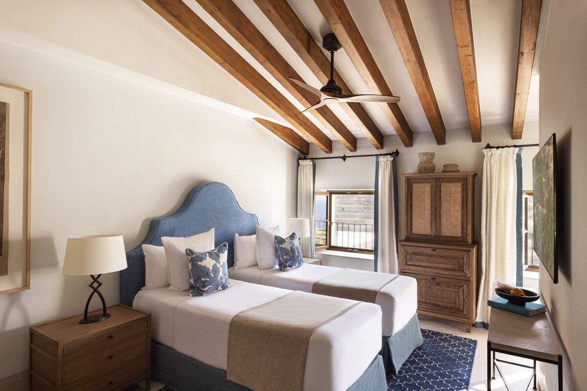 A bedroom with two beds and a ceiling fan