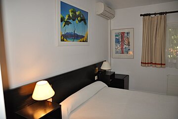 A bedroom with a painting on the wall above the bed