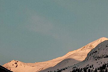 A snowy mountain with a blue sky in the background