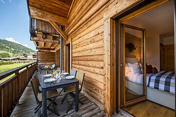 A balcony with a table and chairs in front of a bedroom