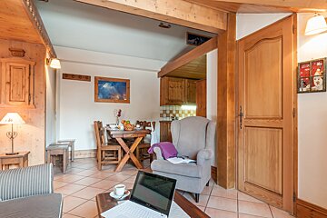 A living room with a chair and a laptop on the table