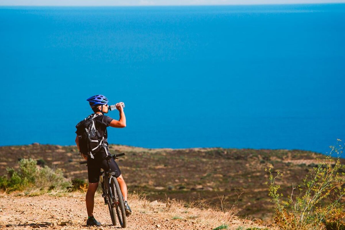A man drinking water from a bottle while riding a bike