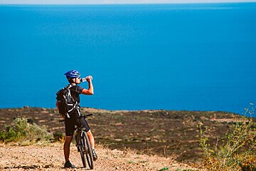A man drinking water from a bottle while riding a bike