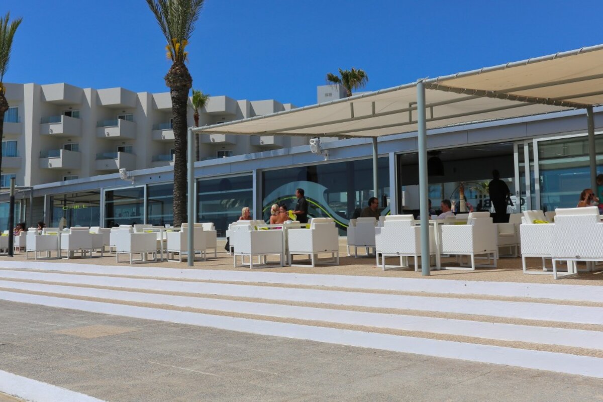 A row of white chairs sit outside of a restaurant