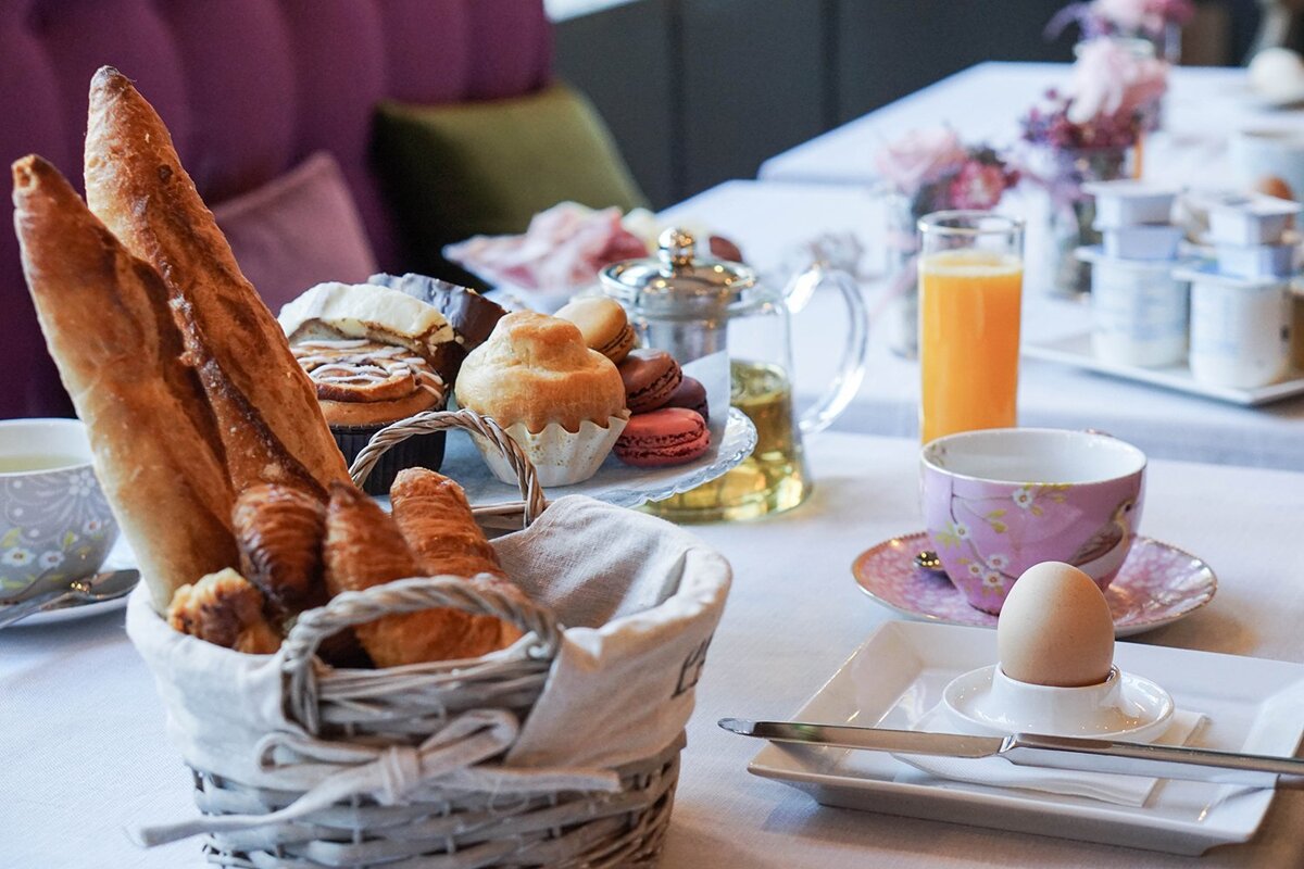A basket of bread sits on a table next to a cup of orange juice